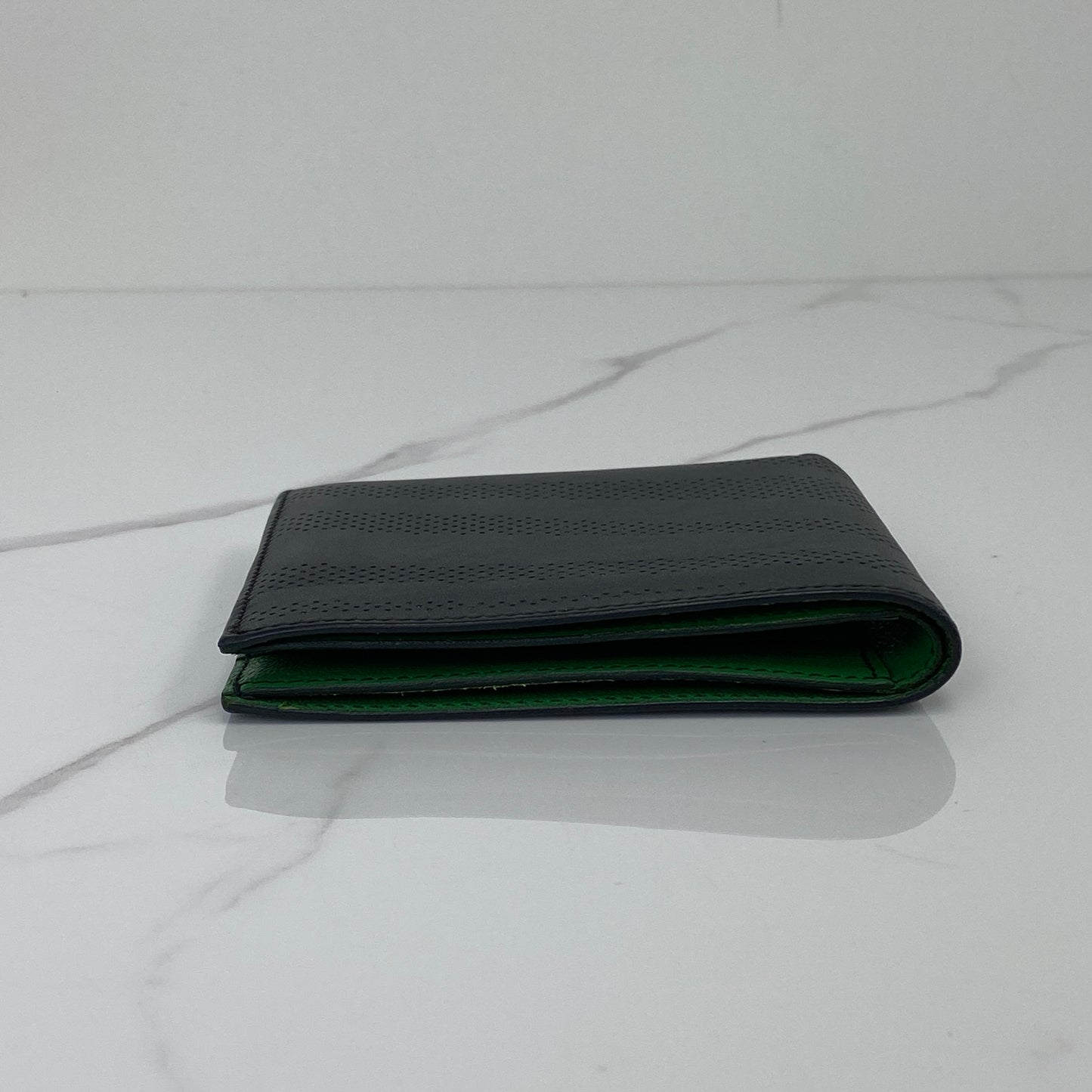 Hermès MC2 Copernic wallet shown from the side, black exterior with green lining
