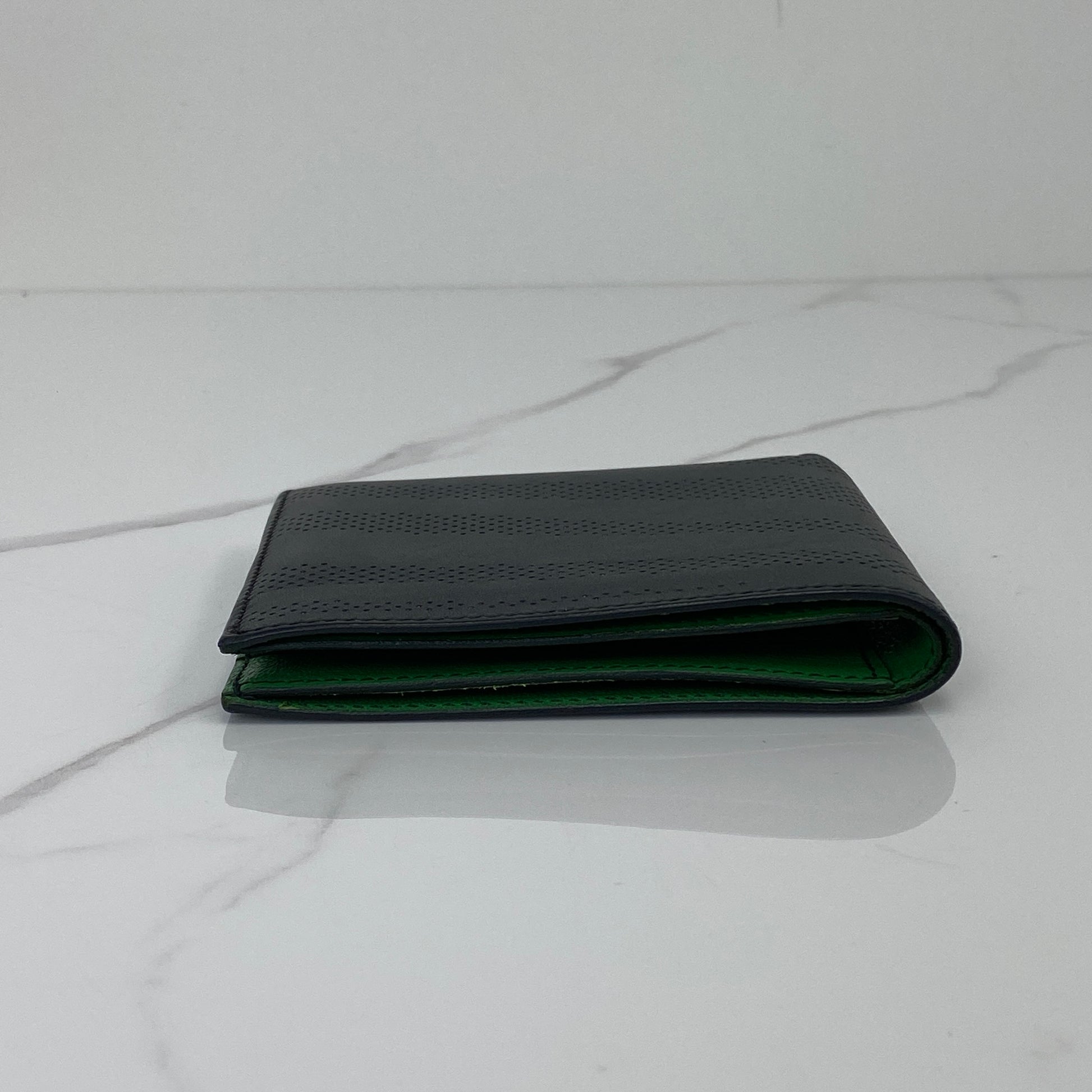 Hermès MC2 Copernic wallet shown from the side, black exterior with green lining