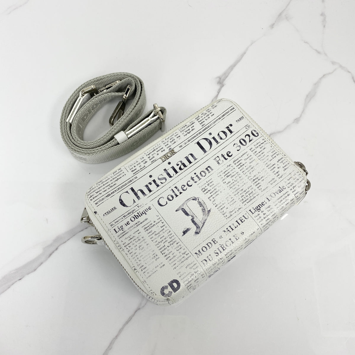 Christian Dior x Daniel Arsham Newspaper Messenger Bag, white and black newspaper-print calfskin, silver-tone hardware — front view