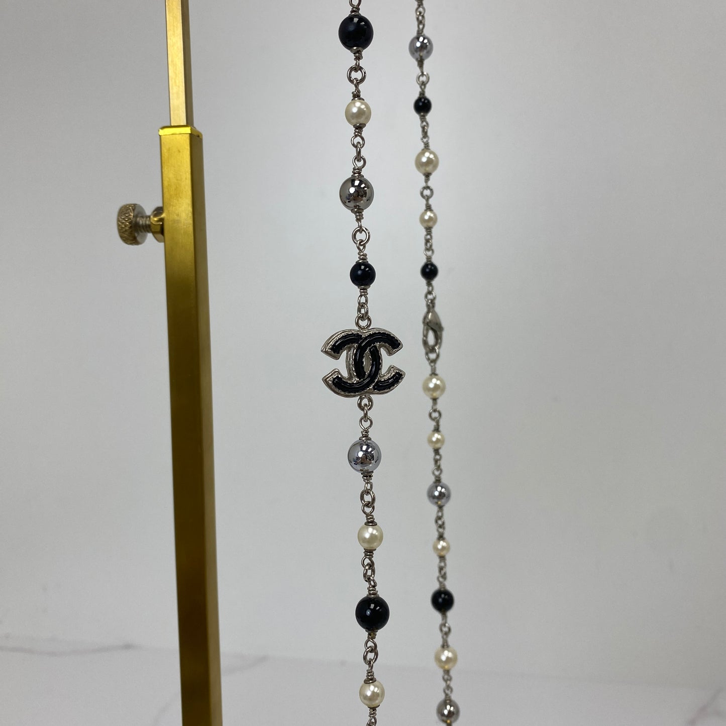 Close-up of the silver-tone interlocking CC charm on the Chanel long necklace